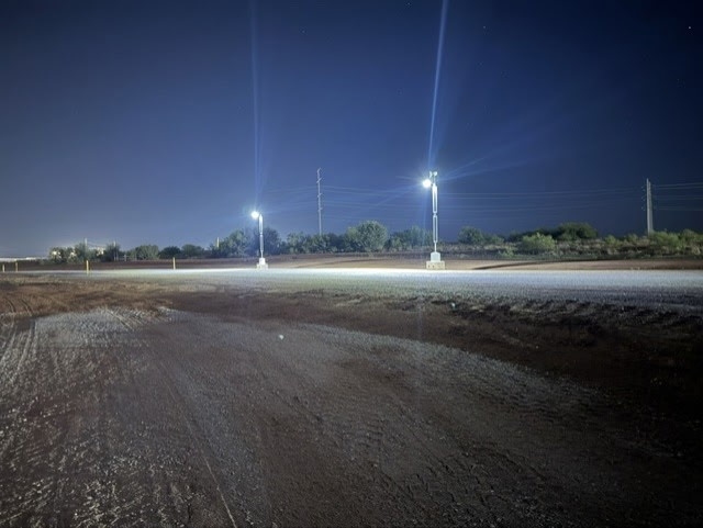 Two KV6 units lighting an access road at night on a live site